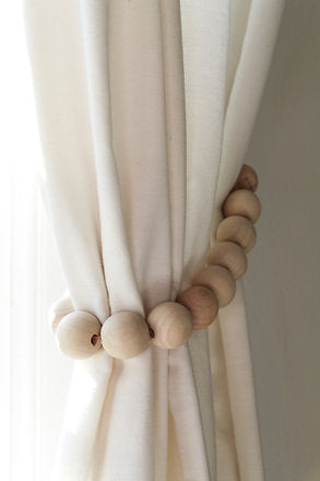 Hug your curtains with a set of wooden curtain tie-backs. This handcrafted piece features natural wooden beads and artificial leather. Handcrafted in South Africa