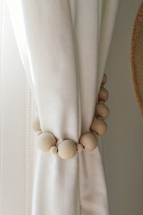 Hug your curtains with a set of wooden curtain tie-backs. This handcrafted piece features natural wooden beads and artificial leather.   SET of 2  Dimensions: 70cm D  Handcrafted in the Western Cape, South Africa.